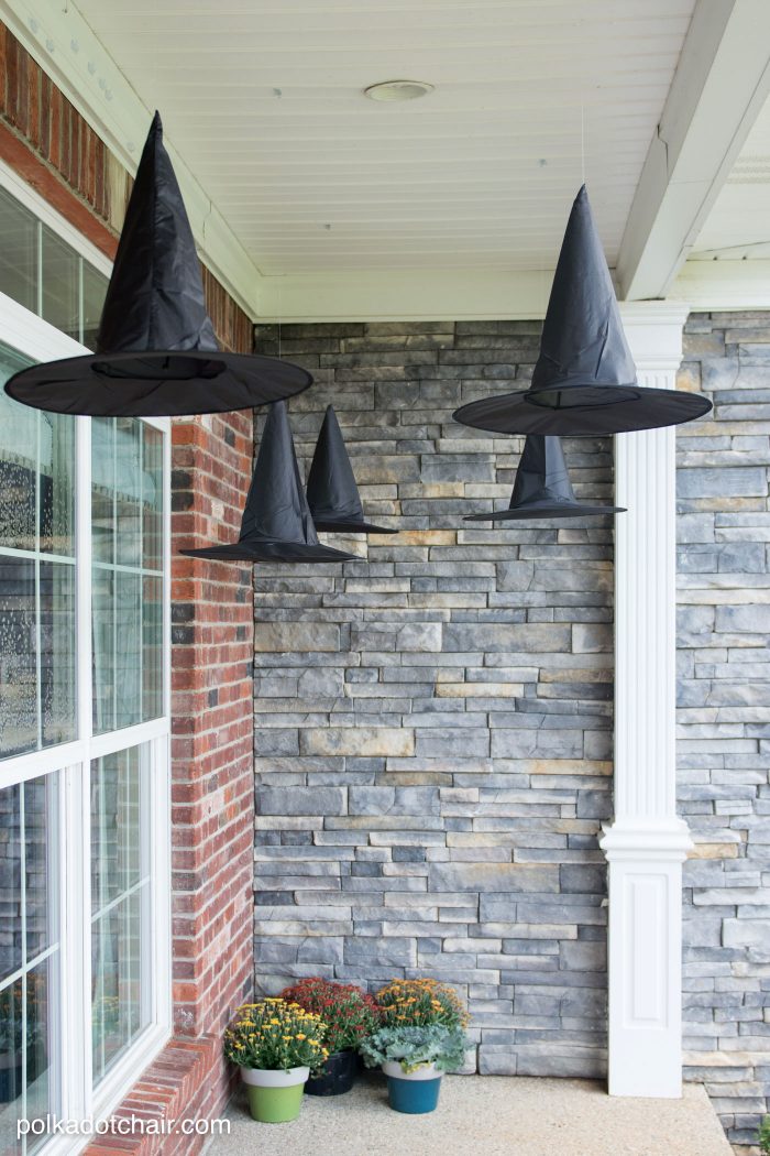black witch hats hanging on front porch. Clever decorating idea for a porch for Halloween, floating Witch's hat luminaries, they even light up at night!