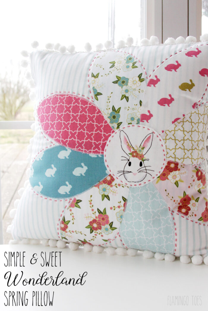 pink, aqua and white floral pillow in front of window