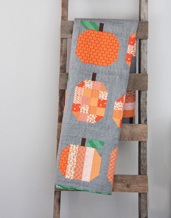 Orange and gray pumpkin quilt hanging on ladder