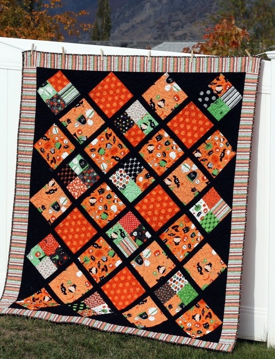 Black and orange halloween quilt hanging on fence