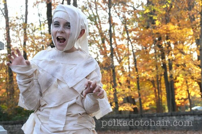 two kids in mummy costumes outdoors in the fall