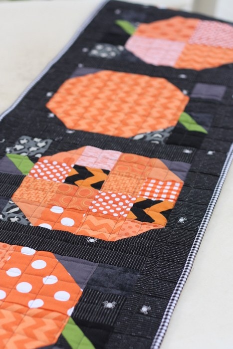 Pumpkin quilted table runner on white table. 