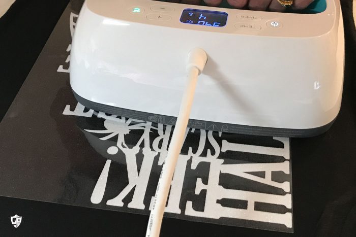 Cricut EasyPress machine creating iron on black tshirt with white text