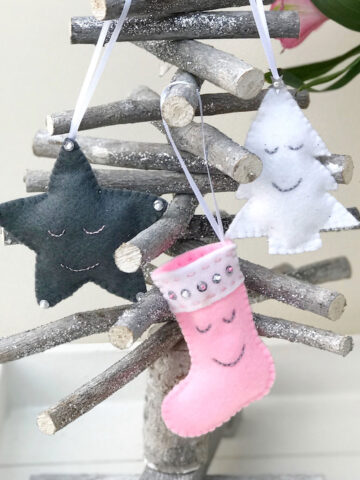 Pink, white and gray Christmas ornaments on wood tree