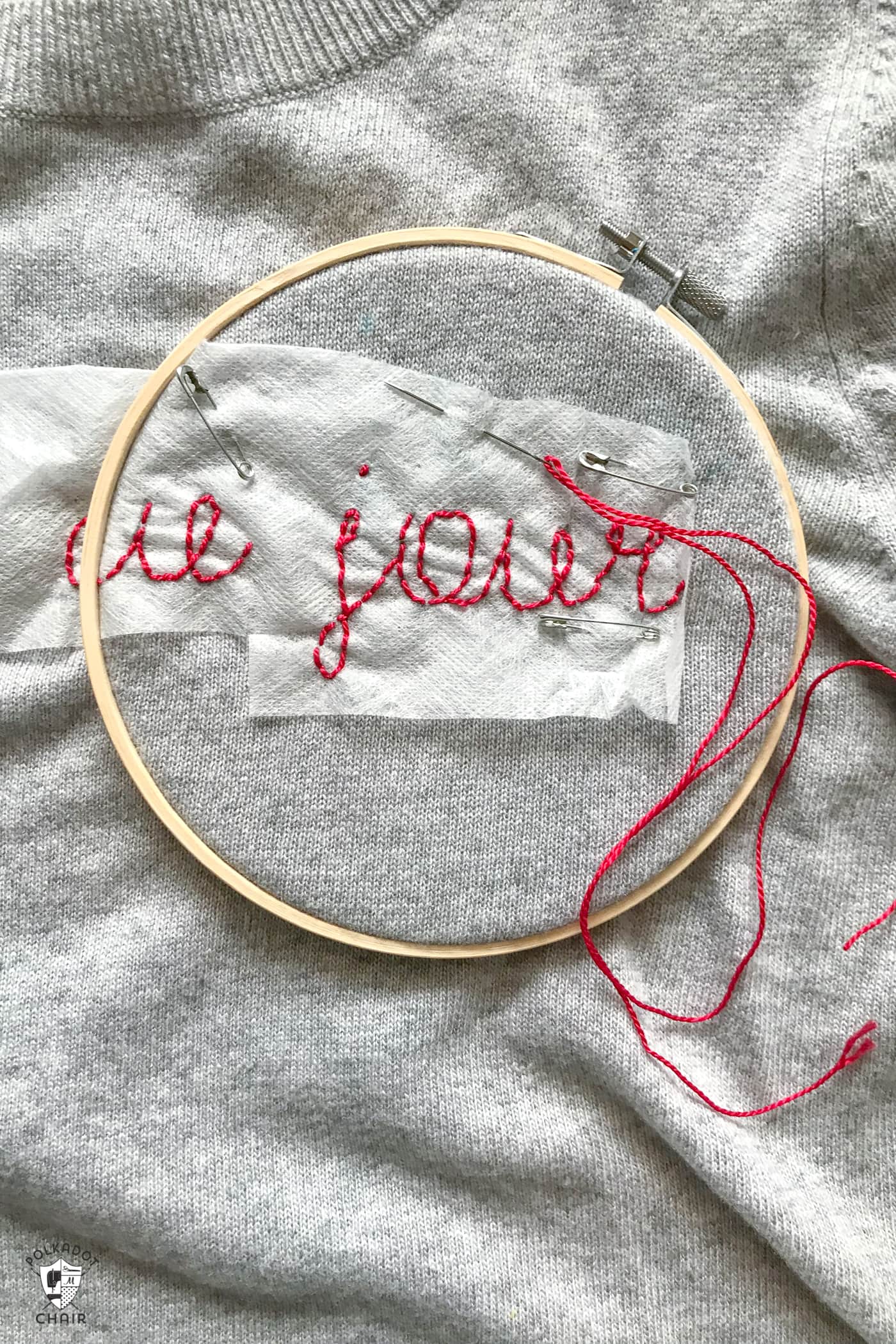 Learn how to make a DIY Embroidered sweater with a fun french quote on it. Includes free embroidery pattern for the quote. A clever way to refashion an old sweater. #DIYEmbroidery #DIYFashion #embroideredsweater #tutorial