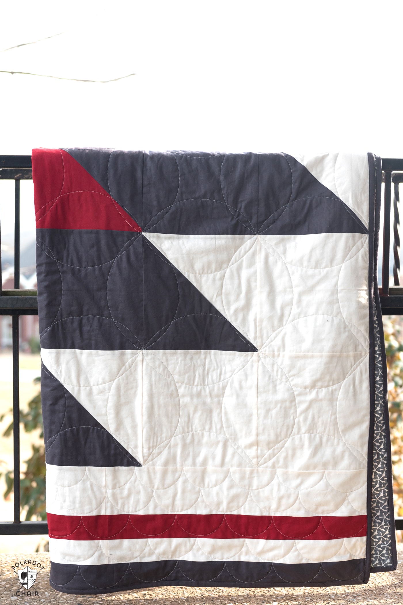 Red, white, and blue quilt on railing out side.