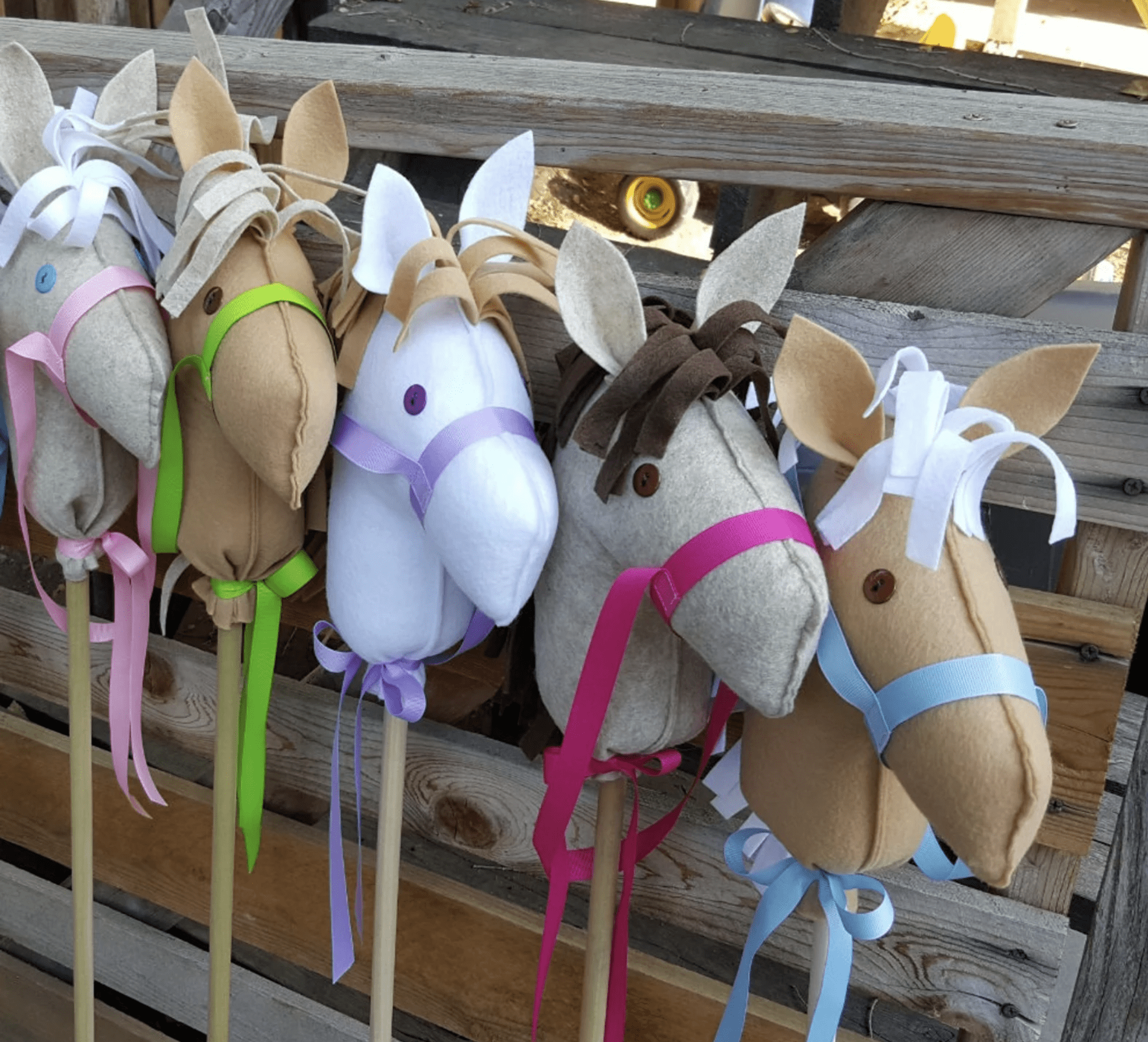 image of 5 stick horses made out of felt in front of barn fence