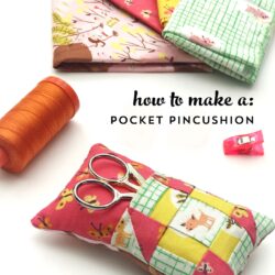 colorful pincushion on white table with fabrics and sewing notions