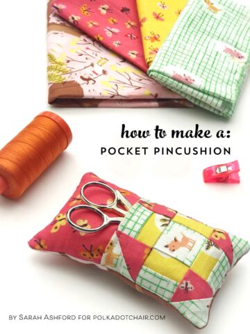 colorful pincushion on white table with fabrics and sewing notions