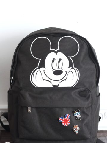 black backpack with mickey mouse iron on sitting on table in front of white wall