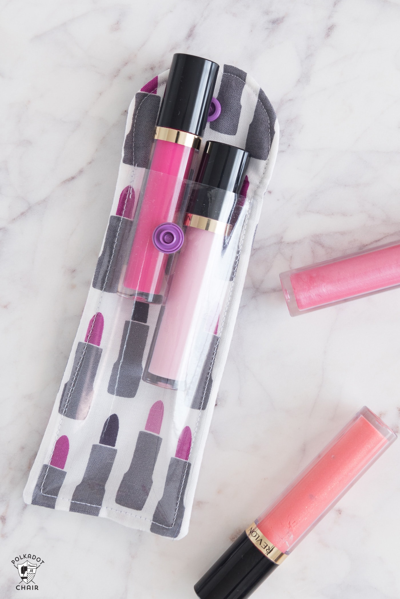 lip gloss pouch on marble tabletop with lip stick next to it