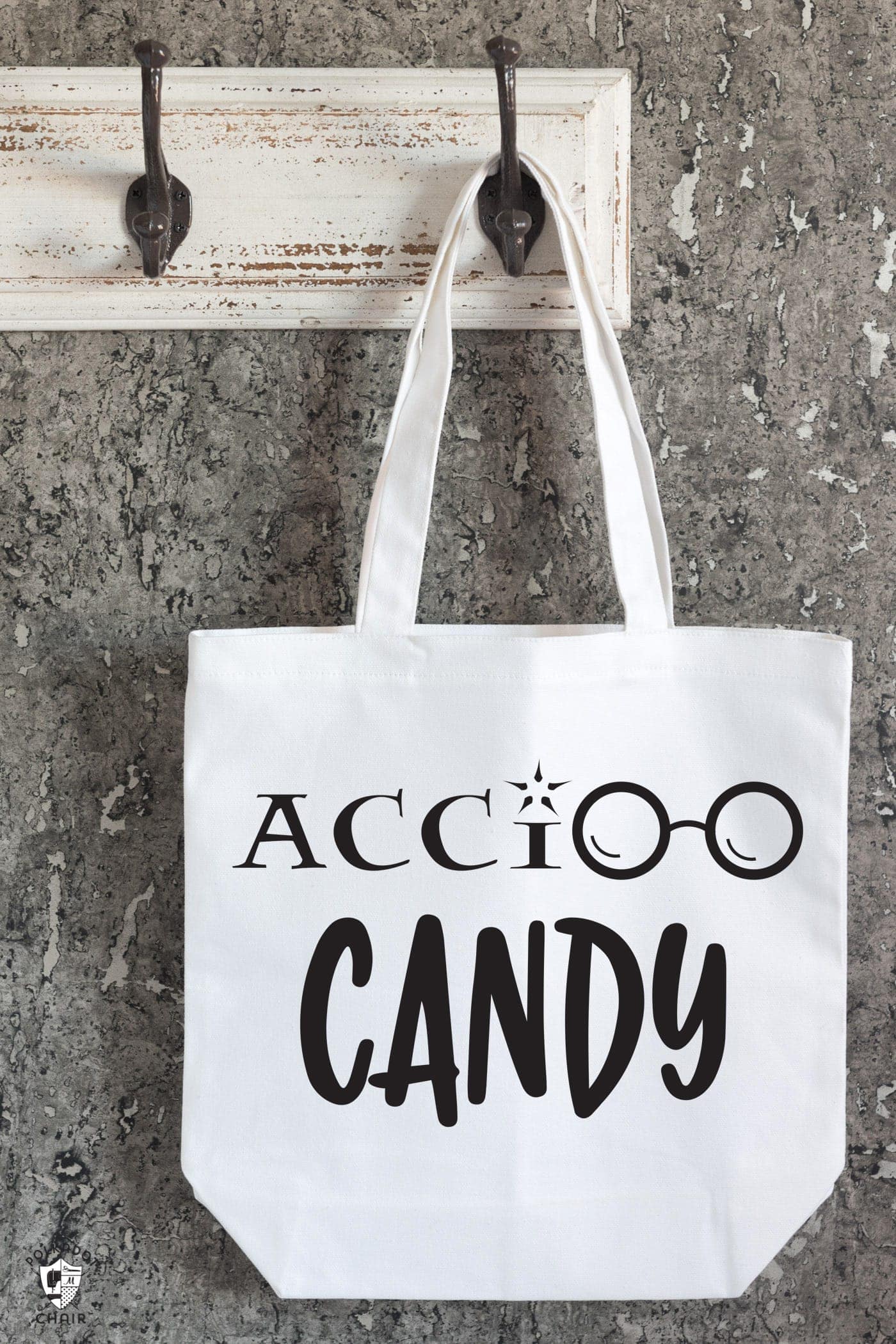 white canvas tote hanging on hook on wall with words accio candy