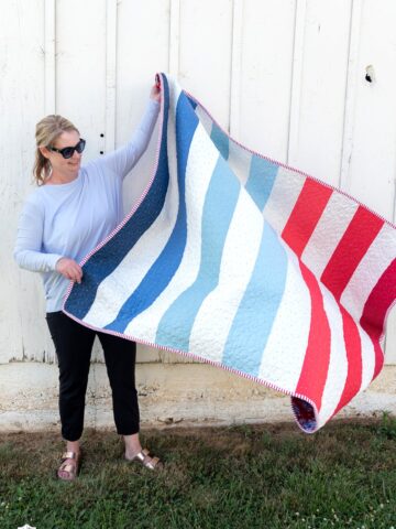 woman holding red white and blue quilt outdoors