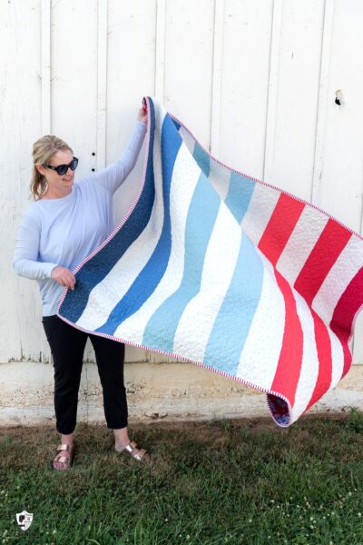 woman holding red white and blue quilt outdoors