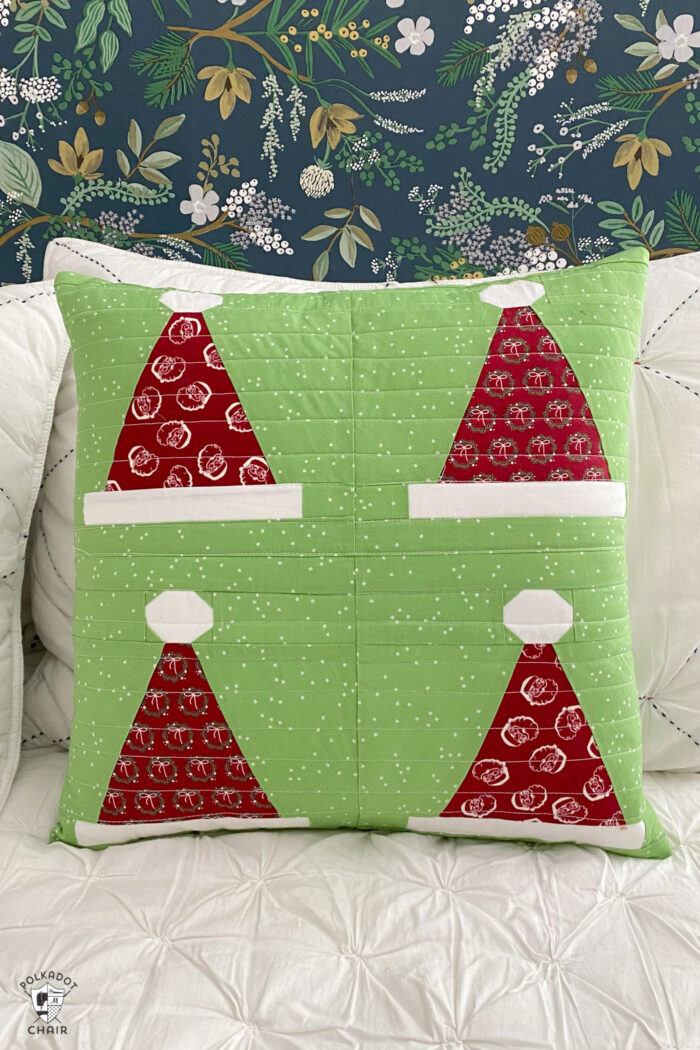 green santa hat pillow on white bed