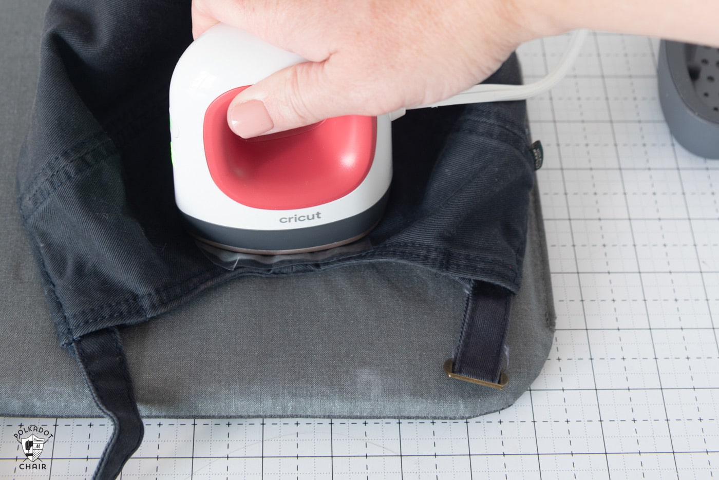 Cricut EasyPress mini being held down on navy baseball cap to iron vinyl on. 