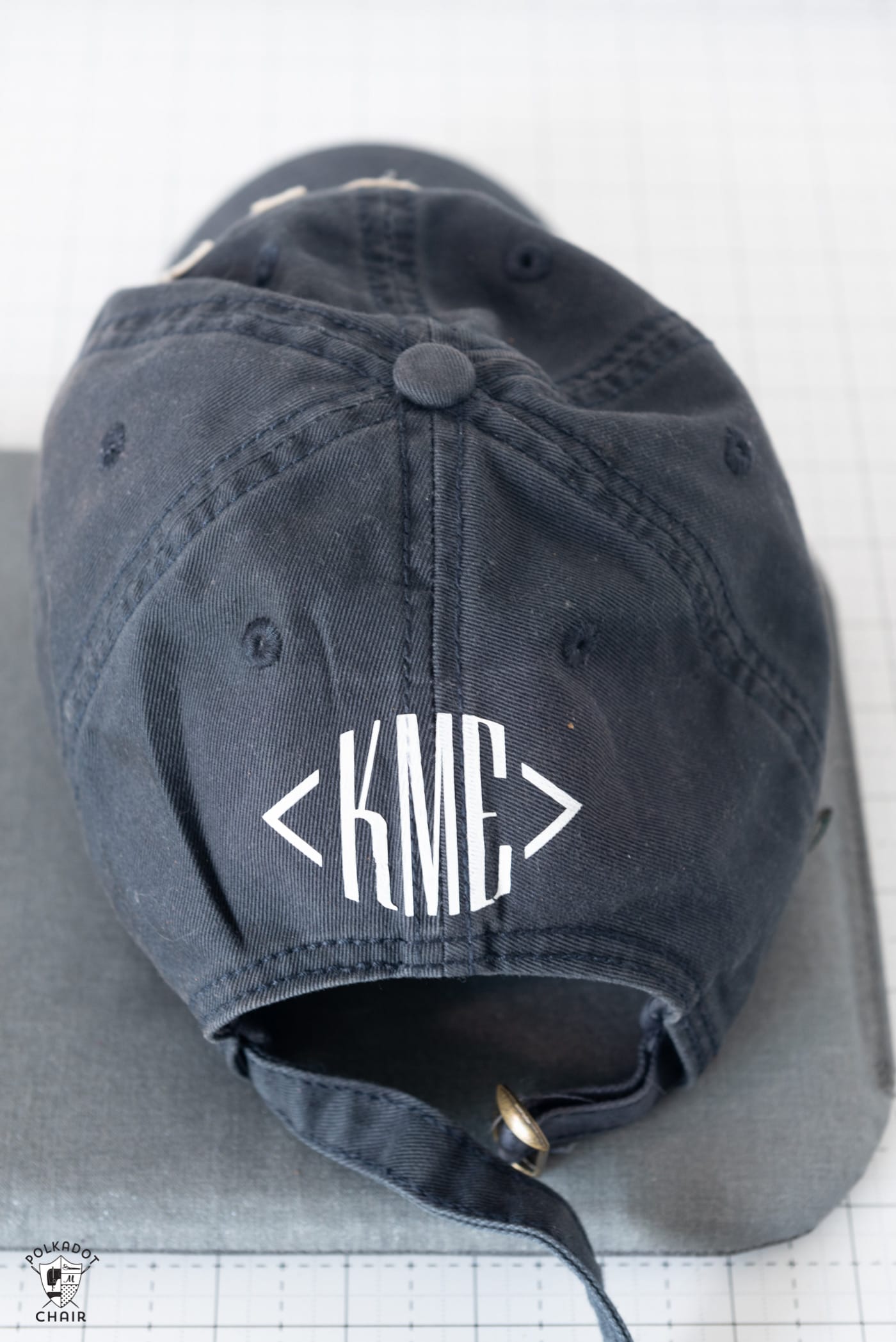  A navy baseball cap with white vinyl monogram "KME" on the back. 