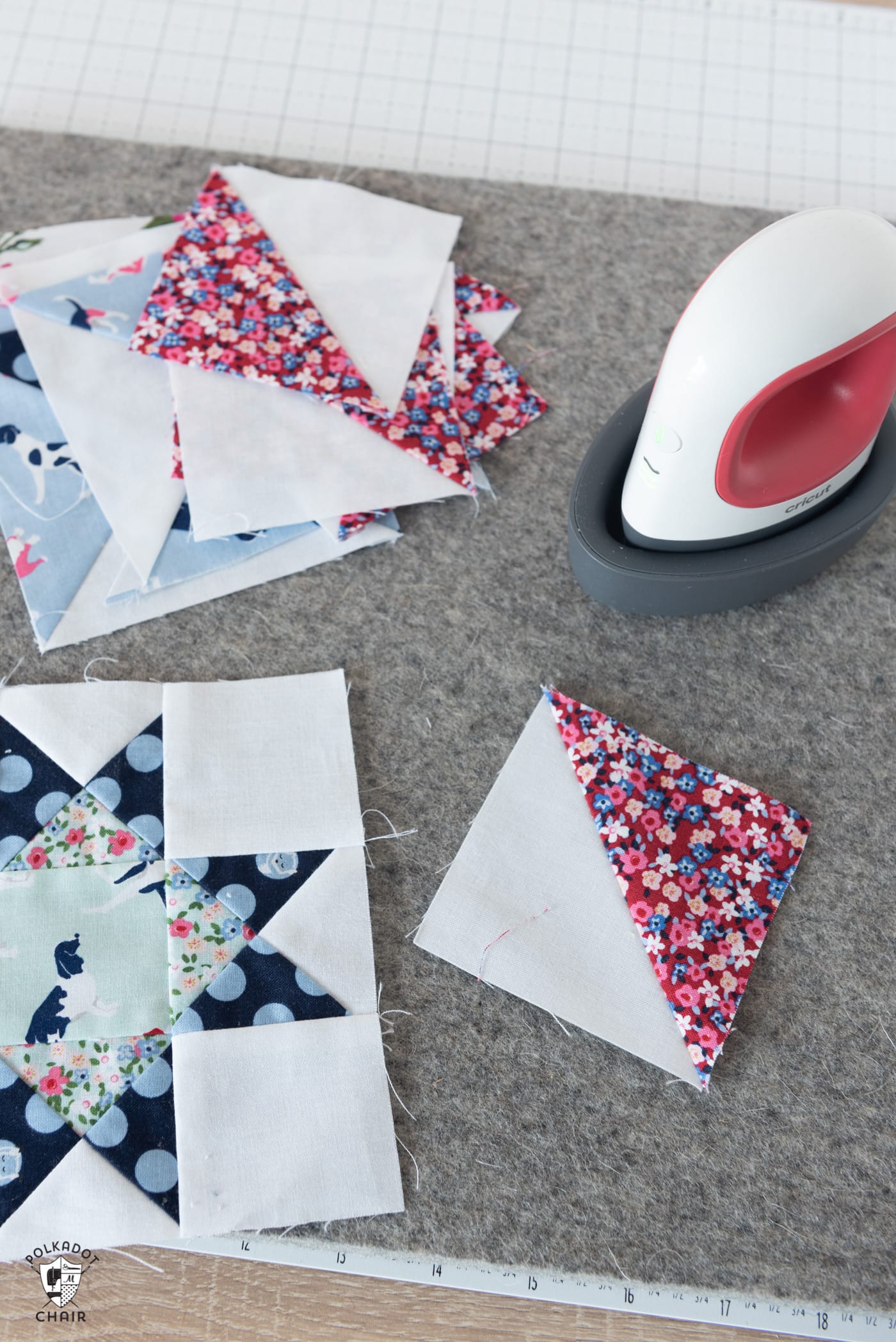 Cricut EasyPress mini on a table next to a pile of quilt squares being pieced together. 