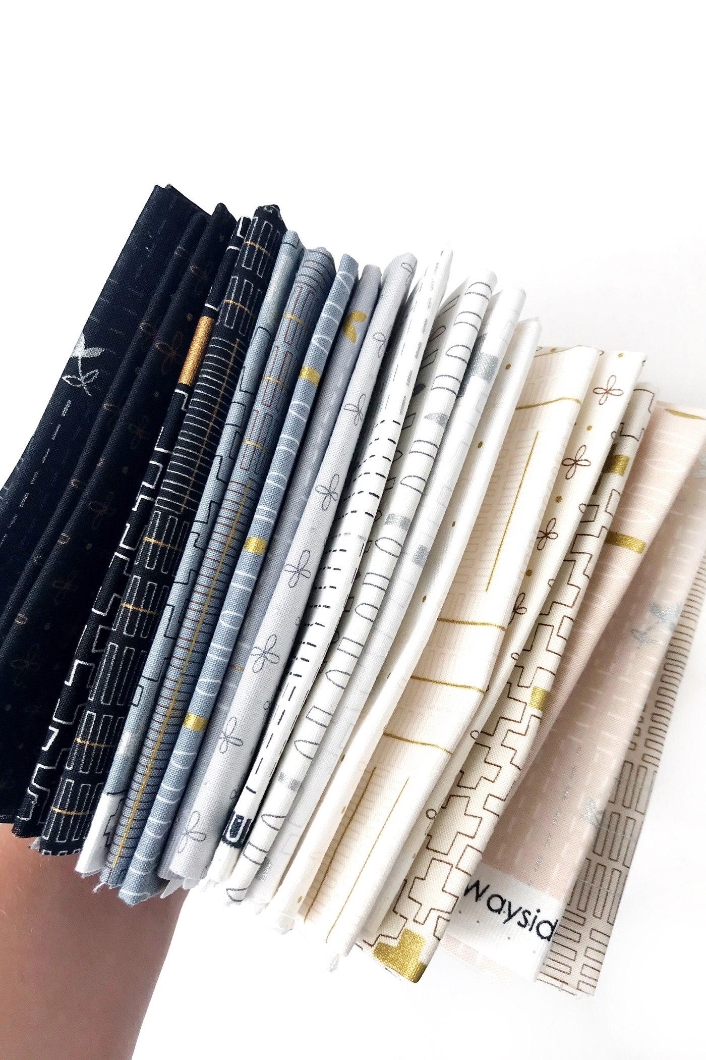 Different folded fabrics being held over a white table