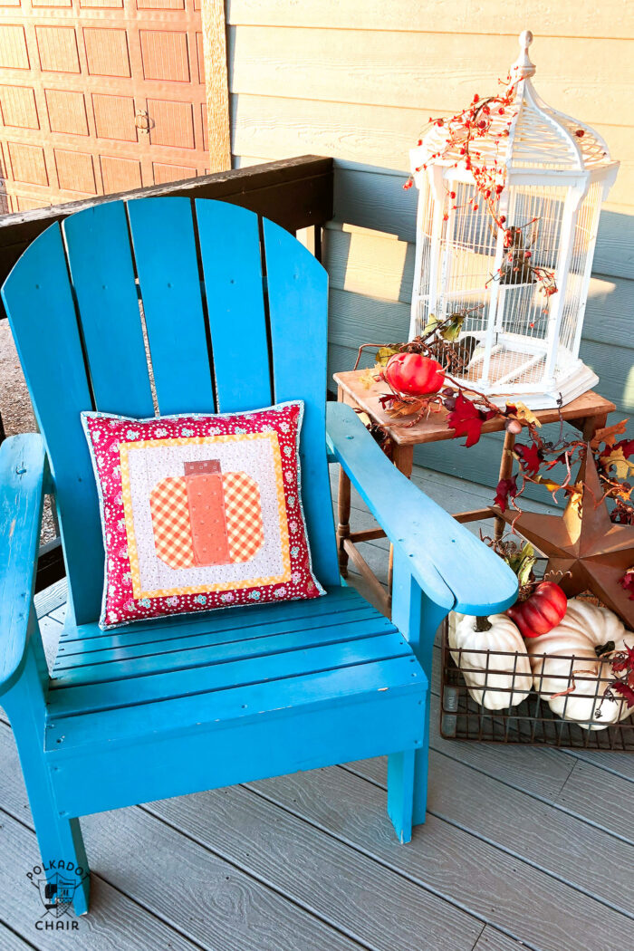 Pumpkin pillow on front porch decorated for fall