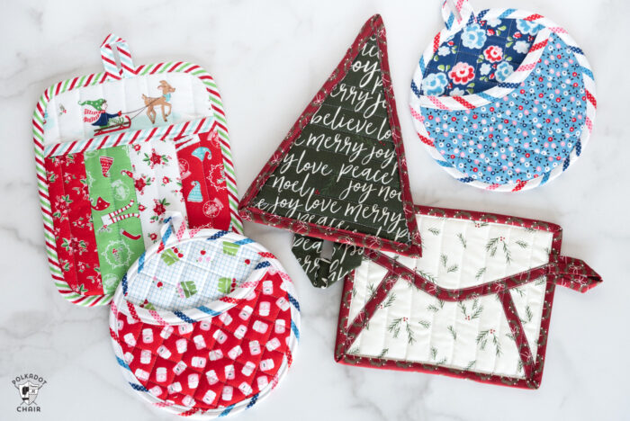 Variety of quilted potholders on white table. 