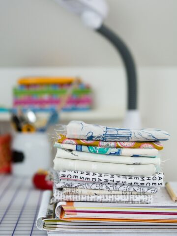 stack of fabric on sewing table