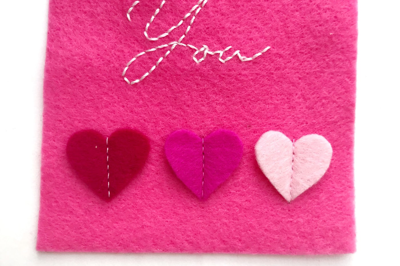 hand embroidered felt gift tags on white table showing detail of stitched down hearts