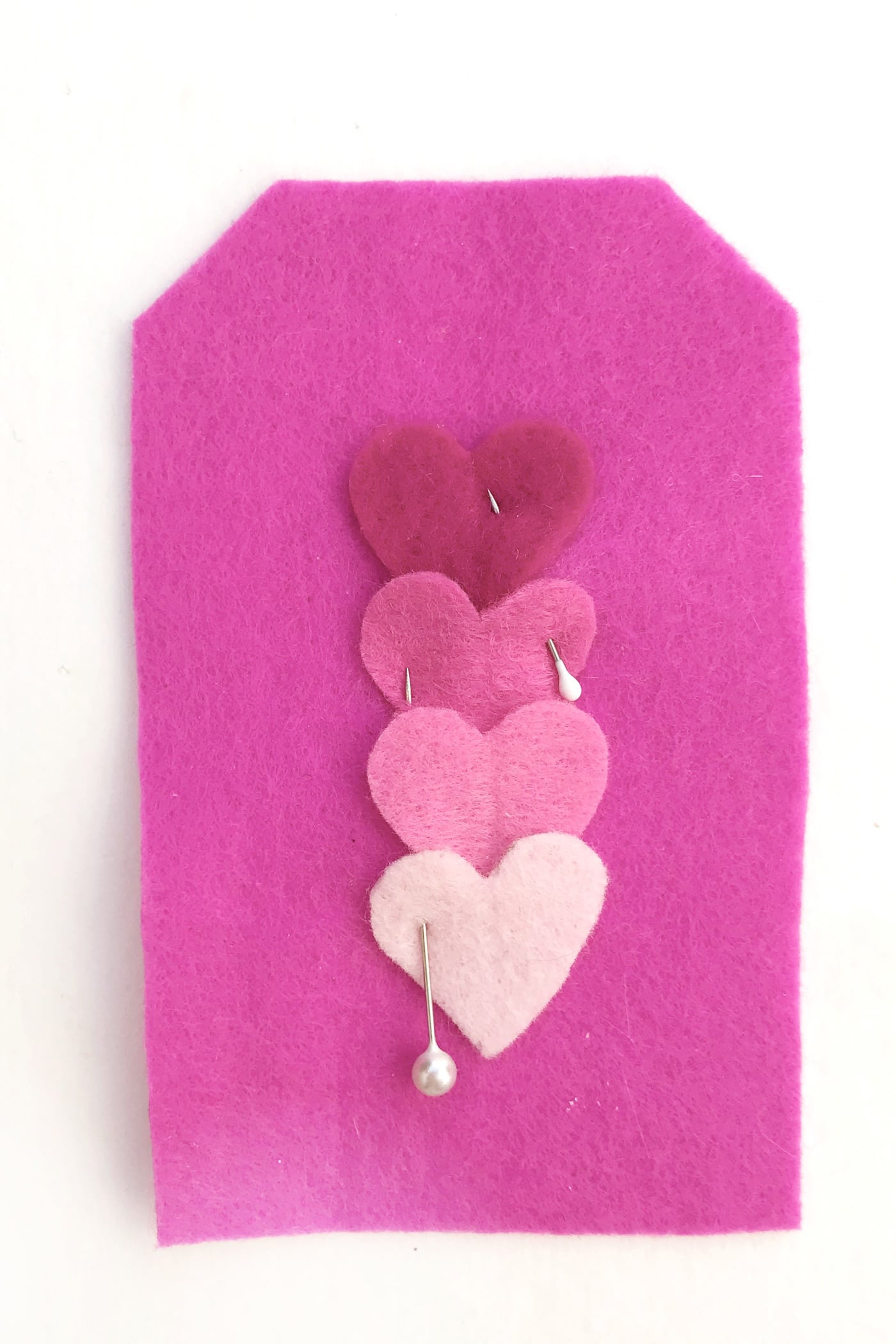 hand embroidered felt gift tags on white table with hearts pinned on