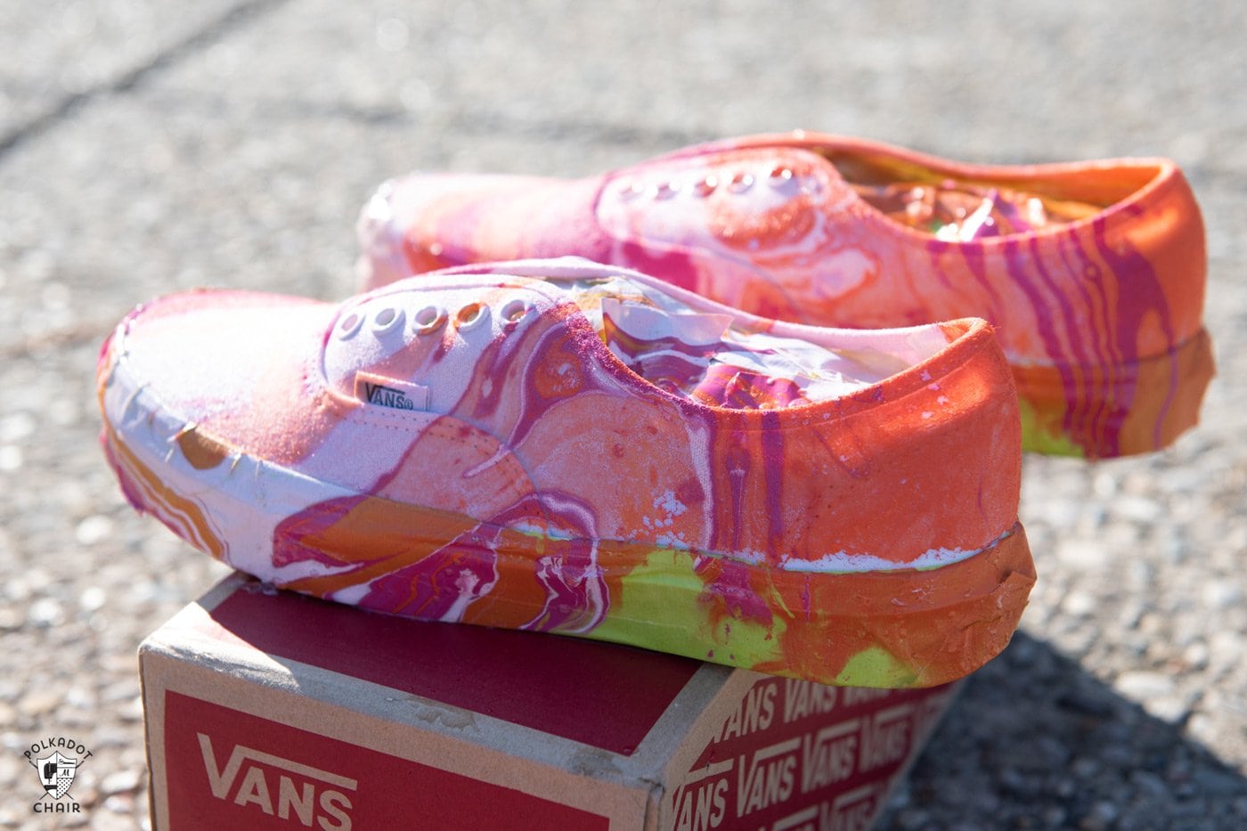 White orange and pink hydro dipped vans drying in the sun on a shoe box after being dipped.