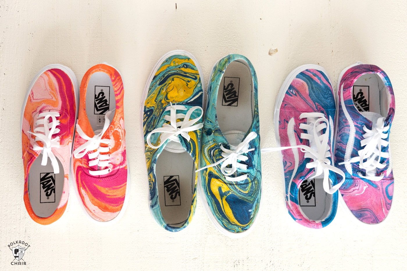 Three pairs of lace up sneakers. One pair is a pink, orange, and white marble, one is pink and blue marble, and the third blue and yellow marble. 