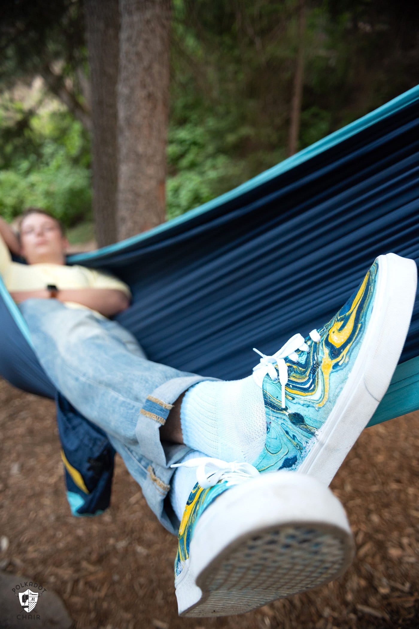 person in a blue hammock wearing blue and yellow hydro dipped vans