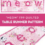 Pink and white MEOW quilted table runner on white tabletop