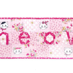 Pink and white MEOW quilted table runner on white tabletop