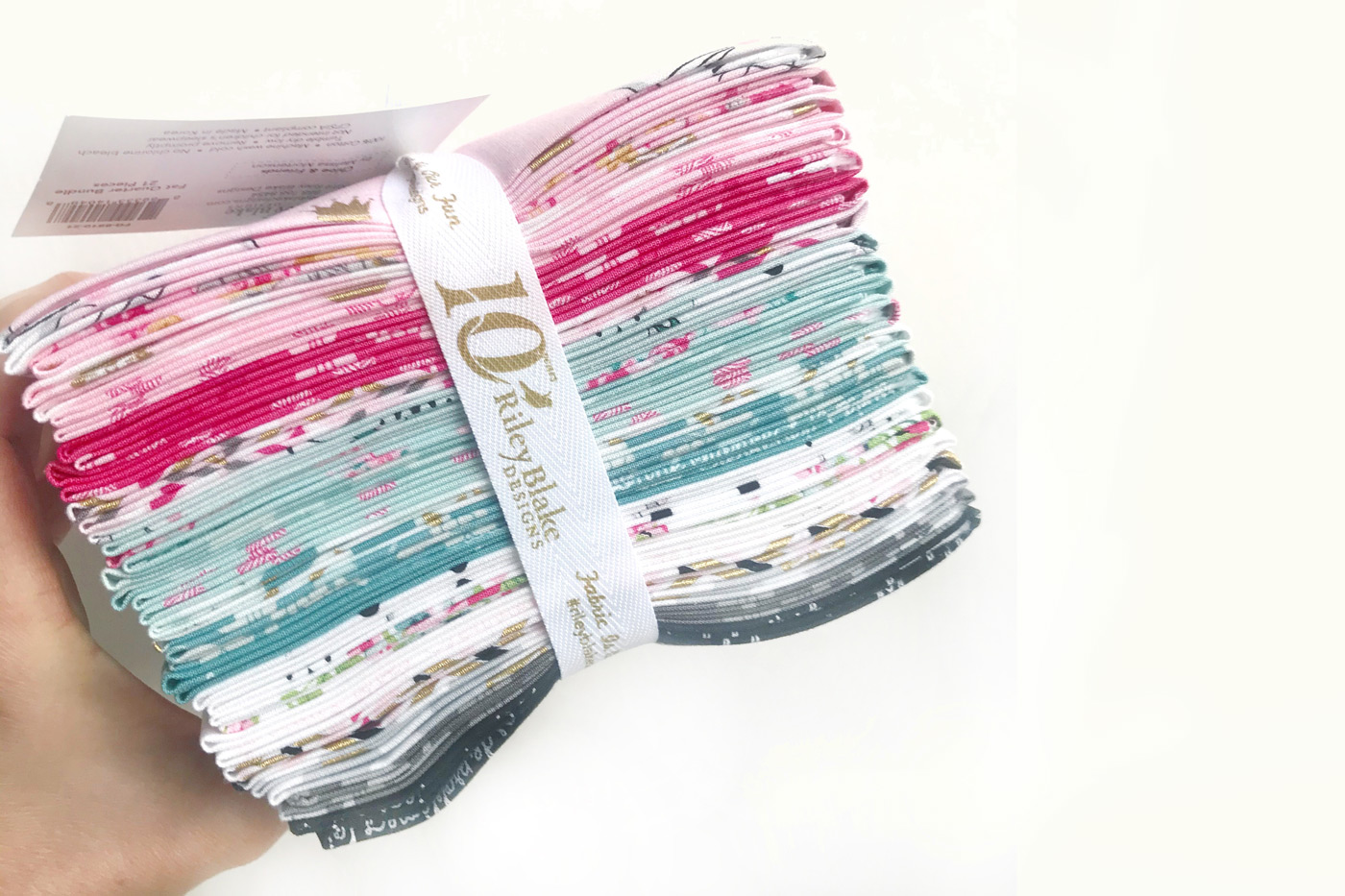 Stack of pink, aqua, white and gray fabrics tied with a ribbon