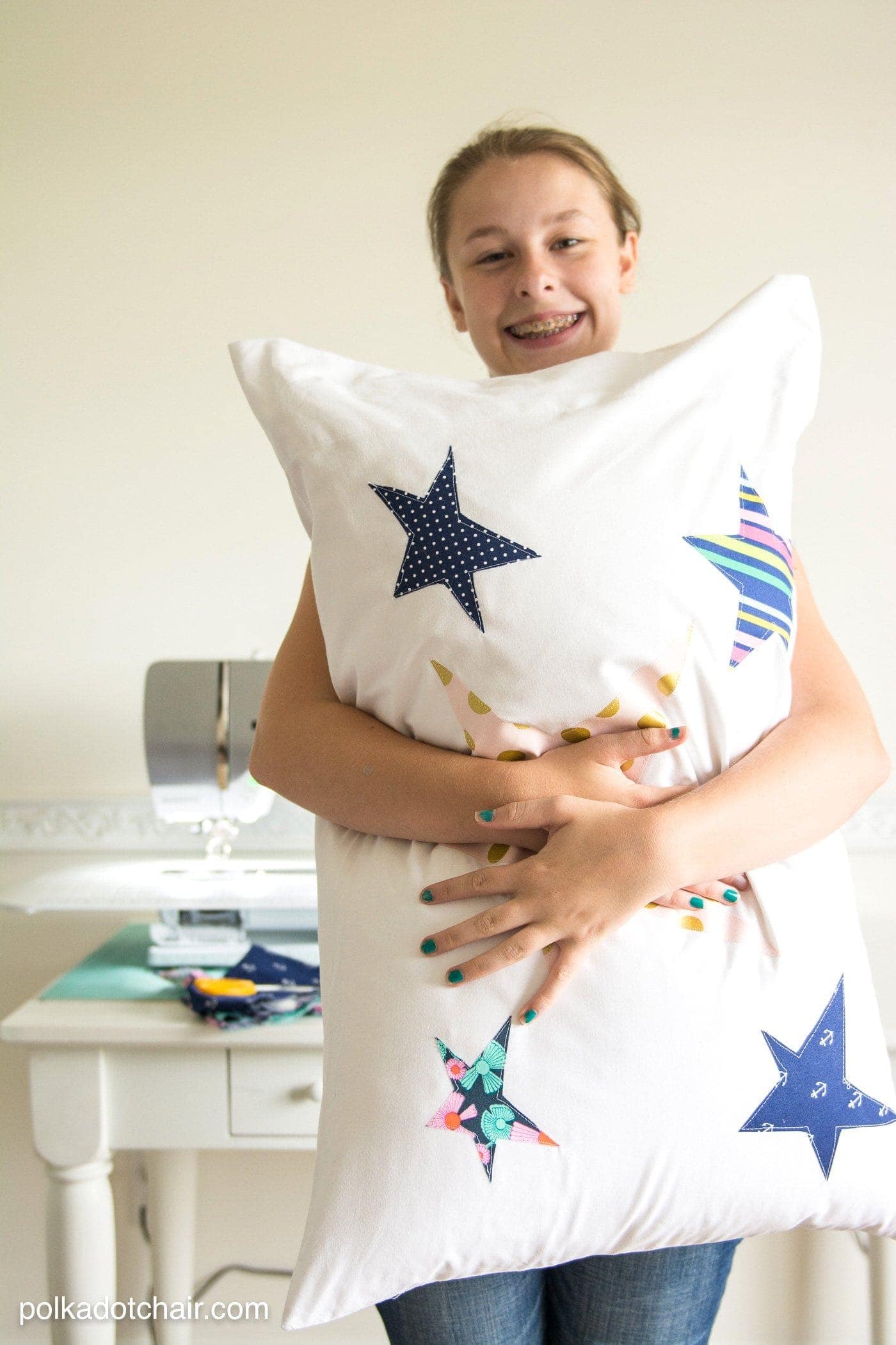 girl holding pillow with sewing machine in background