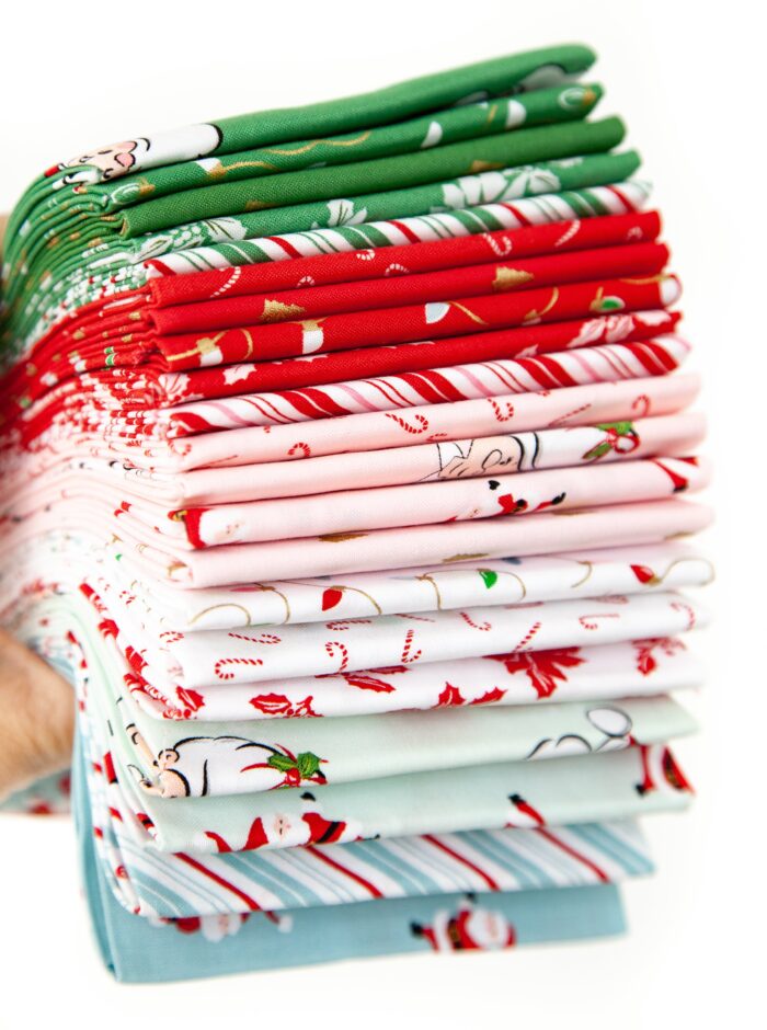 photo of a stack of folded santa claus lane fabric on white background