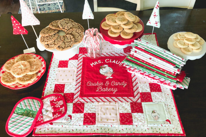 red white and pink christmas table topper with cookies on brown table