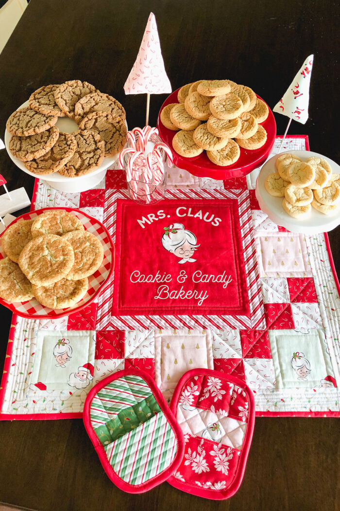 red white and pink christmas table topper with cookies on brown table