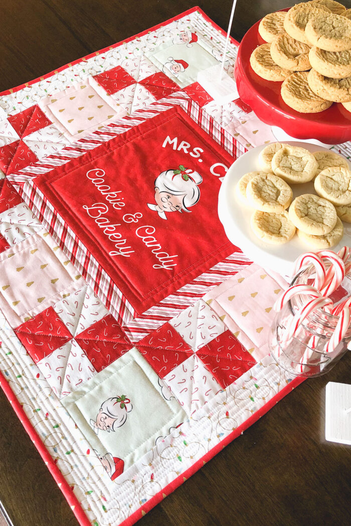 red white and pink christmas table topper with cookies on brown table