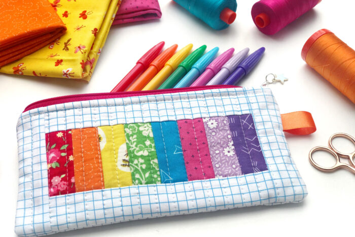 rainbow pencil pouch on white table with spools of thread and fabric