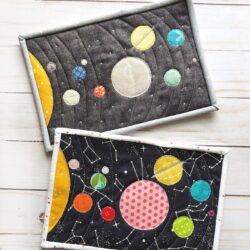 Colorful fabric Solar System mug rug on white wood table