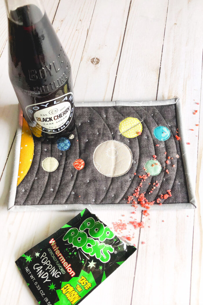 Colorful fabric Solar System mug rug on white wood table