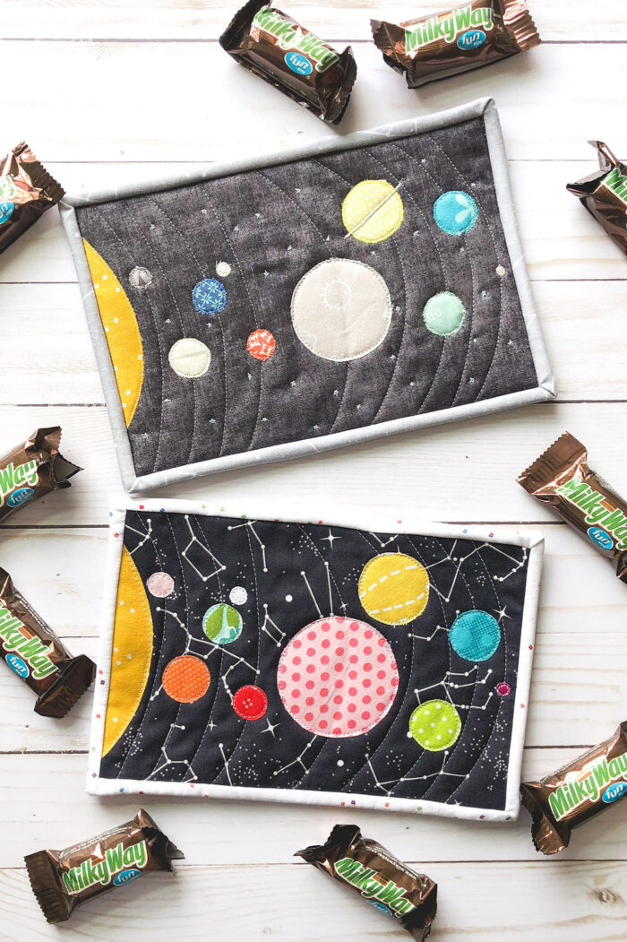 Colorful fabric Solar System mug rug on white wood table