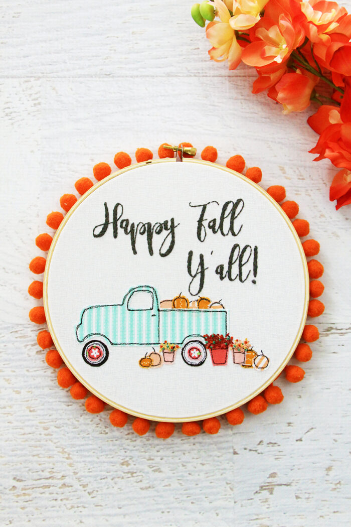 fall embroidery hoop art with truck & pumpkin motifs with pom pom edging. 