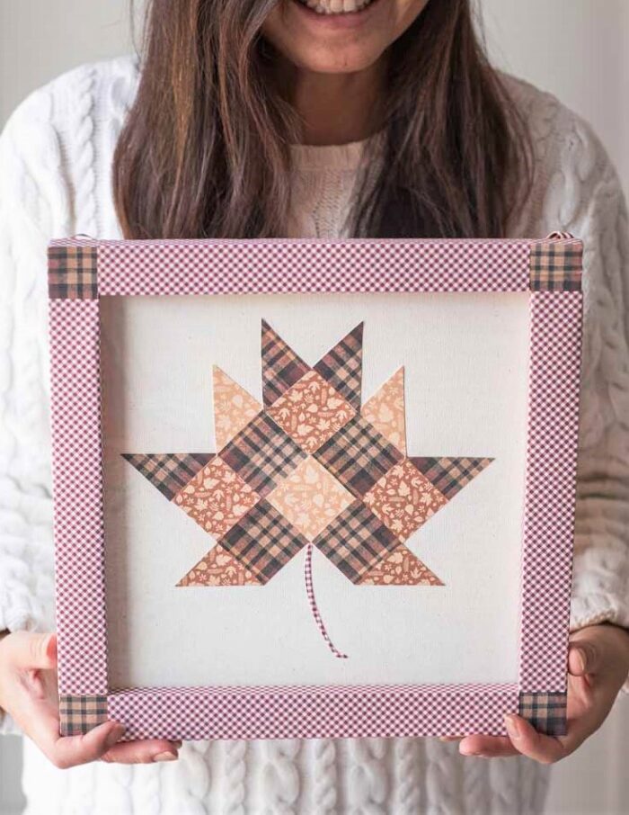 Paper quilt block leaf art held by woman in white sweater