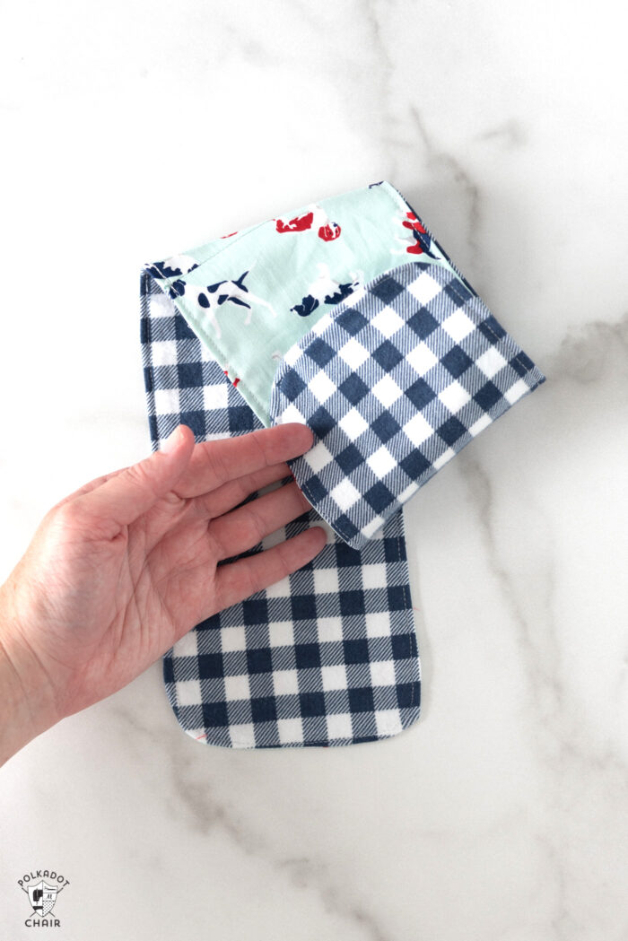 blue baby burp cloths on white marble countertop with hand holding cloth