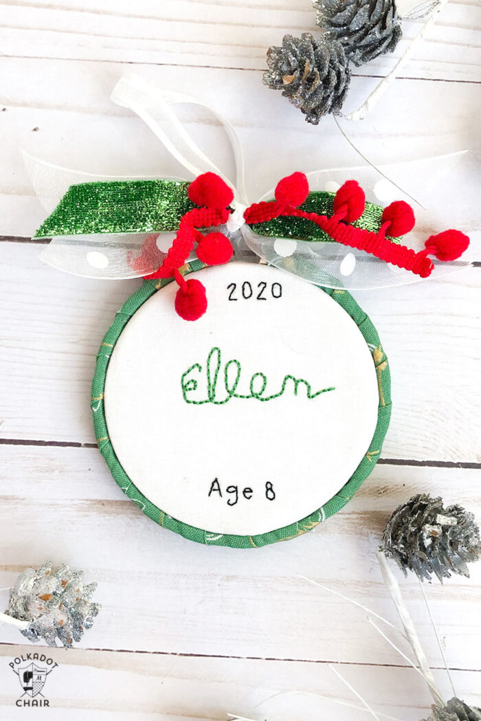 hand embroidered christmas ornaments with childrens names on white wood table