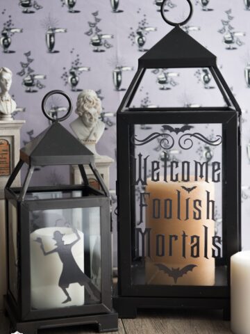 two black lanterns with lettering in front of purple wallpaper