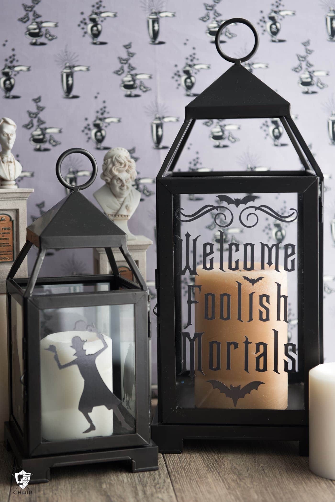two black lanterns with lettering in front of purple wallpaper