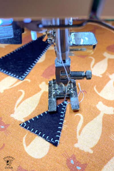 close up of sewing machine foot sewing applique stitches.